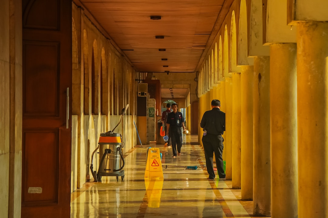 people-walking-down-a-long-sunlit-hallway-with-columns-dknqy7y-olk